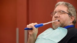A patient uses the GripEazy Extend to brush his teeth.