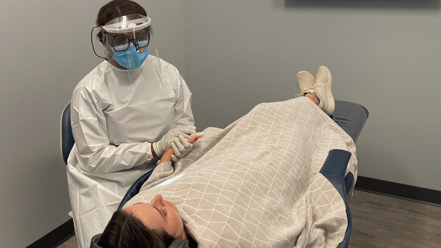 The assistant of Vitalize Dental comforts a nervous patient.