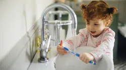 Child rinsing their toothbrush with water