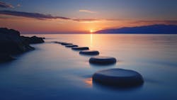 steppingstones going out over water into the sunset steppingstones going out over water into the sunset