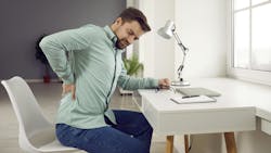 man sitting at a desk rubbing his sore back man sitting at a desk rubbing his sore back