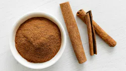 a bowl of ground cinnamon and some cinnamon sticks a bowl of ground cinnamon and some cinnamon sticks