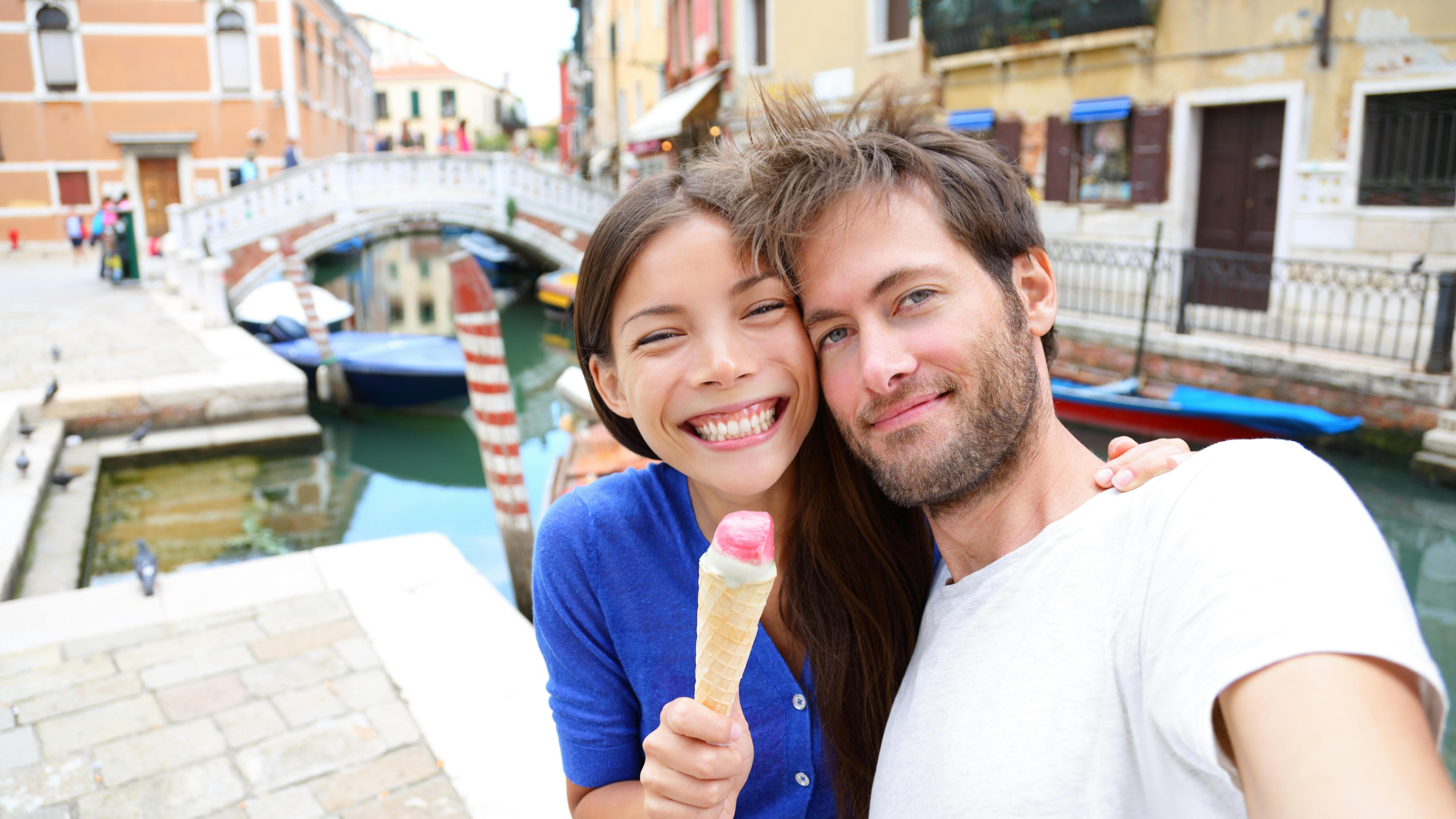 a woman and a man in Italy taking a selfie and holding a gelato