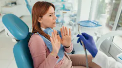 Young woman refusing dental treatment raising her hands in fear