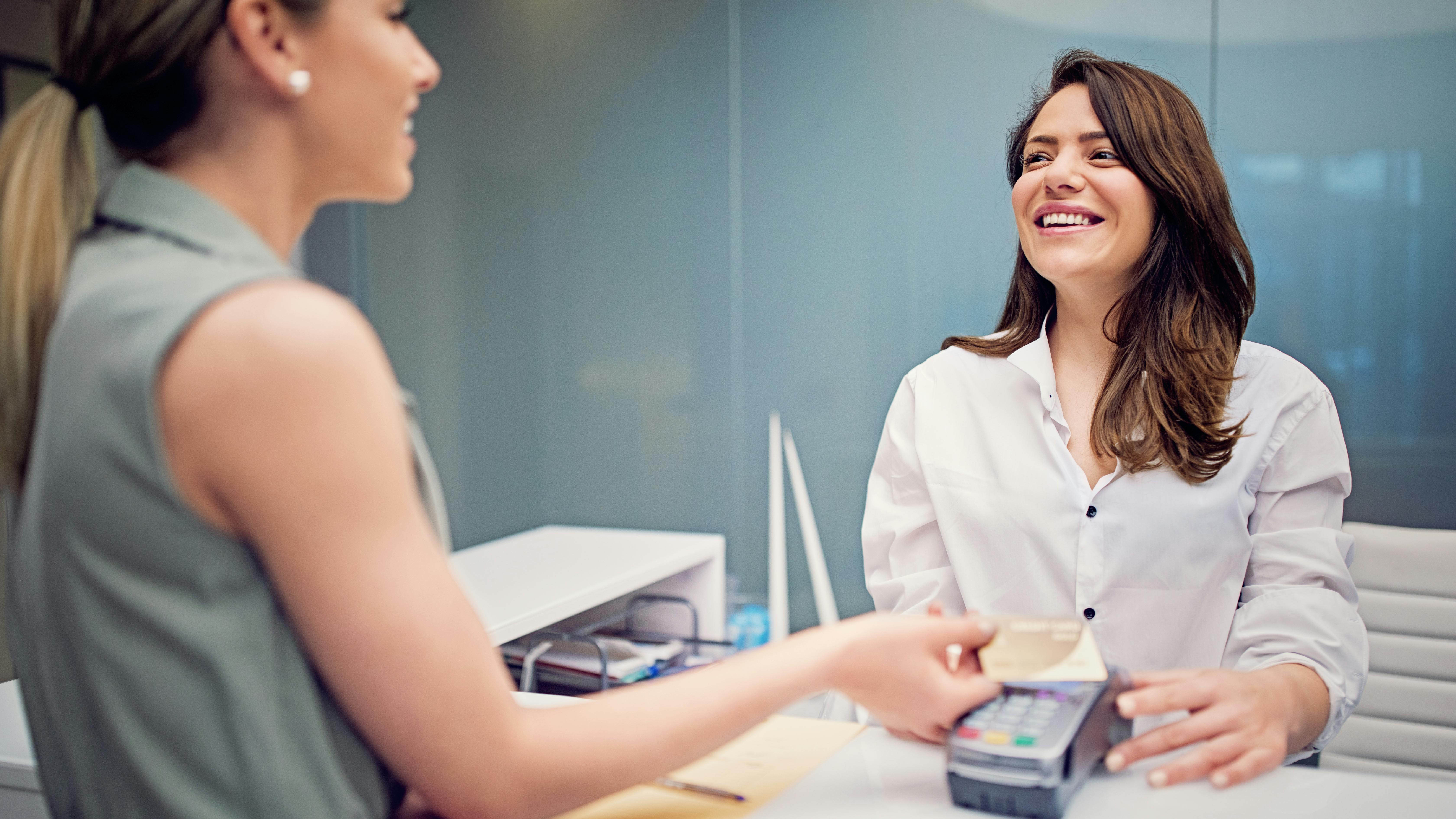 female patient paying at the front desk of a dental office