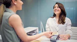 female patient paying at the front desk of a dental office