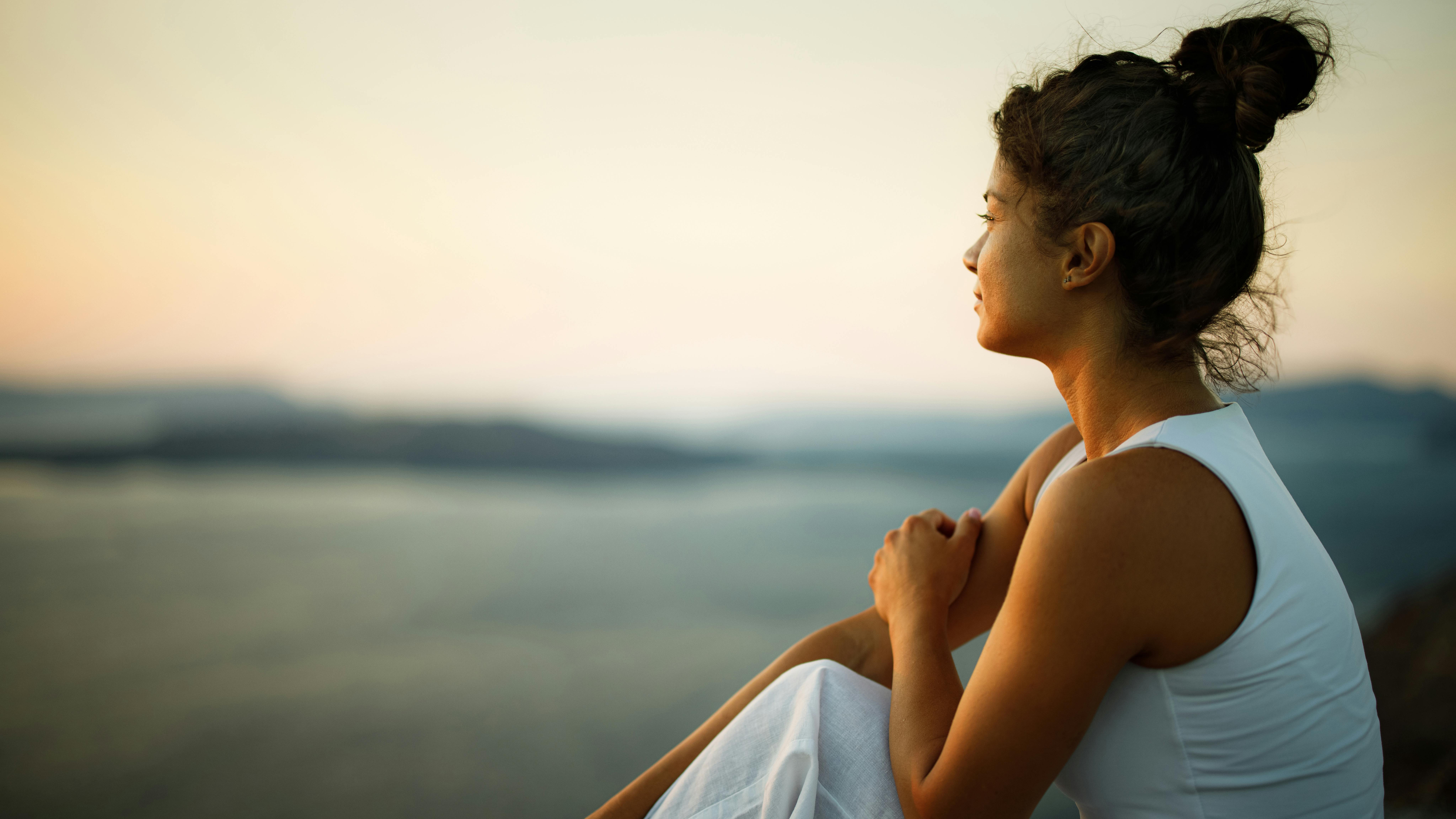 woman in a reflective mood sitting outside gazing into the distance
