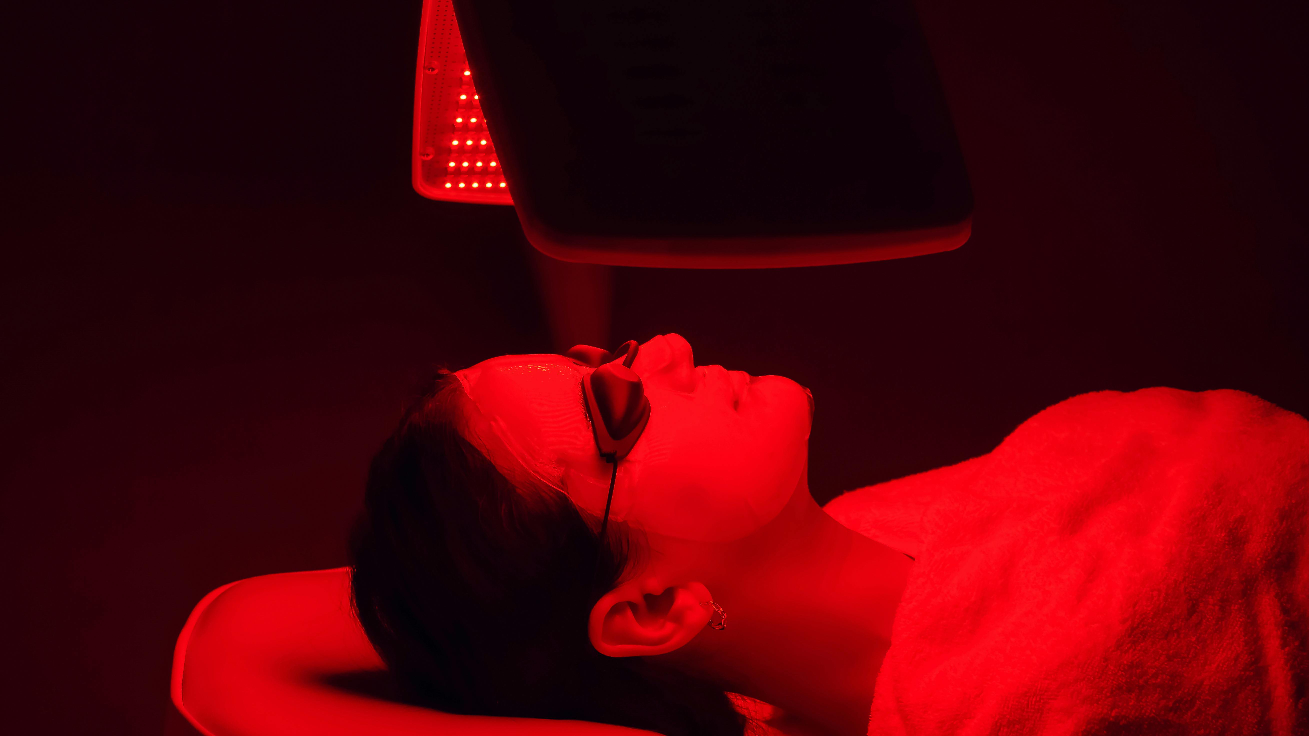 woman lying on a bed receiving red light therapy