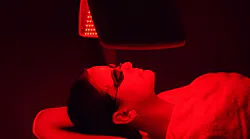woman lying on a bed receiving red light therapy